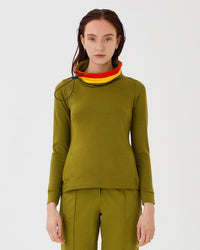 Close-up front view of an olive green merino wool Twiggy pullover jumper by Šumska, featuring a wide collar with vibrant red and yellow stripe panels, paired with olive green hiking pants.