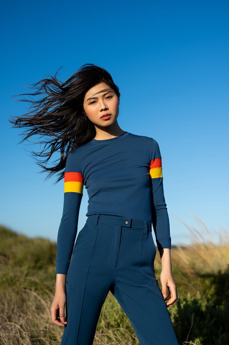 A woman wearing a blue long sleeve Merino t-shirt paired with blue softshell pants.