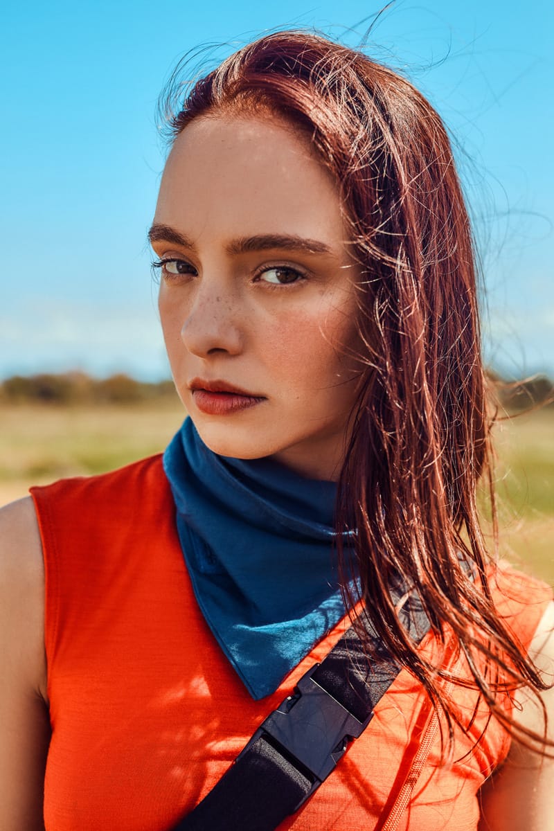 Close-up of a woman wearing a blue Merino snood paired with a red sleeveless merino t-shirt.