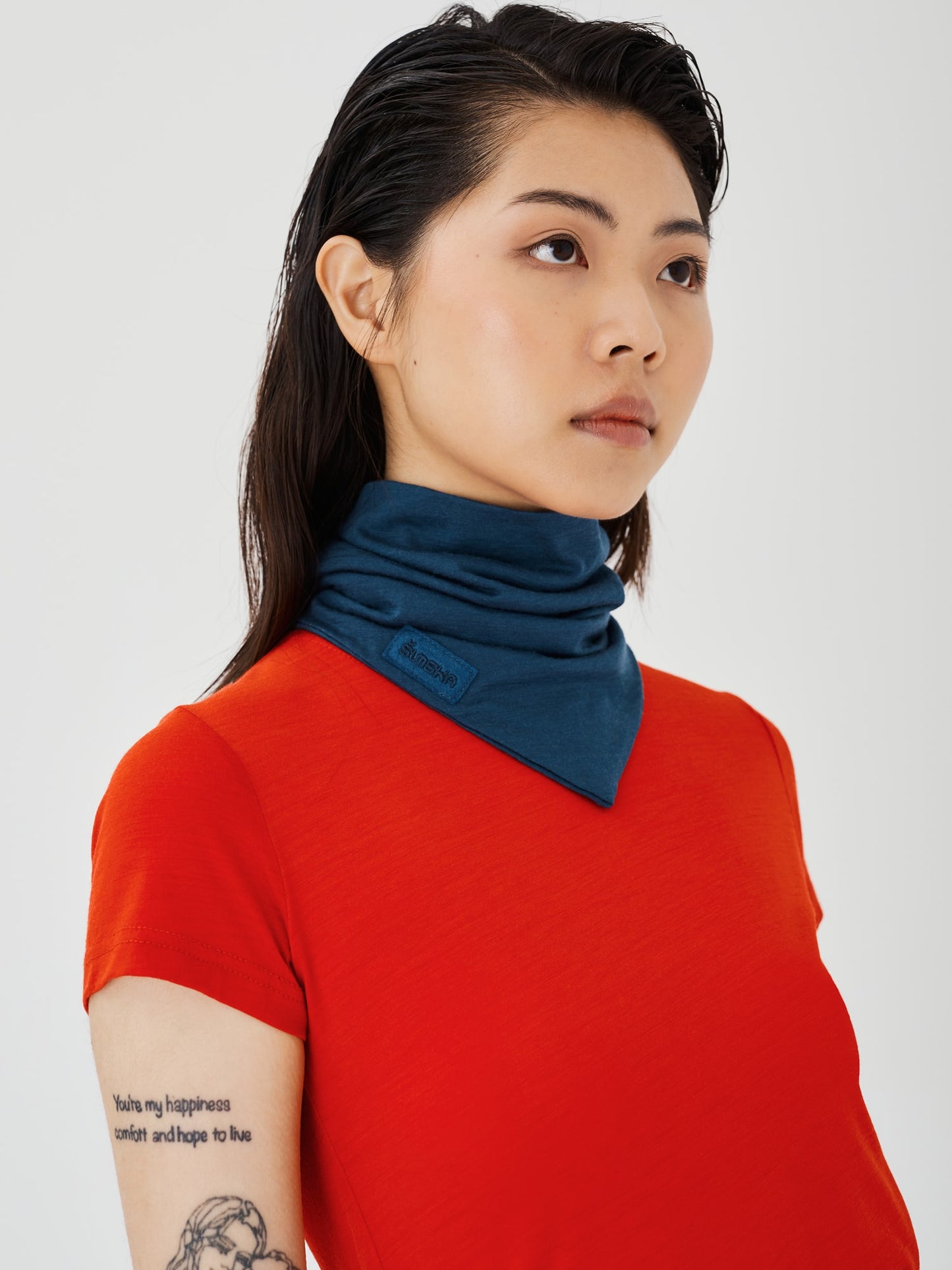 Front angle close-up of a woman wearing a blue merino wool double-layered neck snood by Šumska, paired with a red classic T-shirt, showcasing the warm and versatile design.