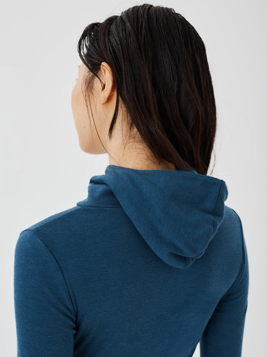 Back view of a women's blue merino wool hoodie by Šumska, showcasing the hood design and slim, comfortable fit.