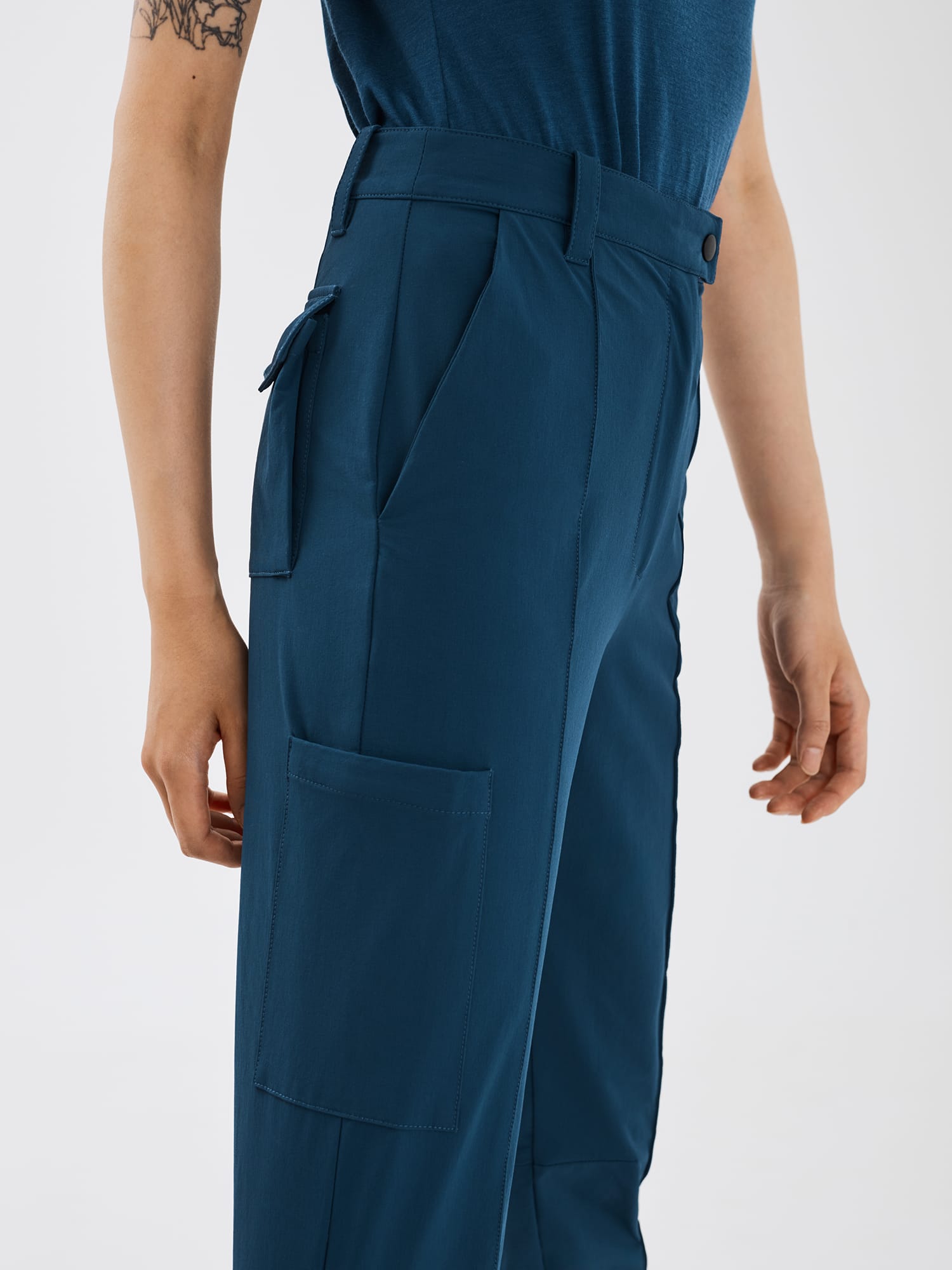 Close-up side view of blue Softshell Hiking Pants by Šumska, showing construction details including hand pocket, side pocket, back pocket features, and front fold seam.