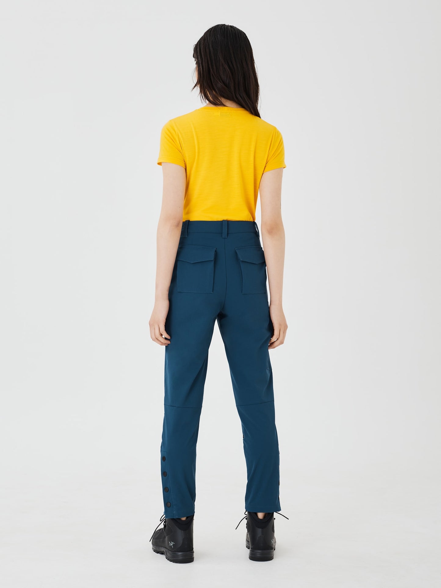 Full back view of blue Softshell Hiking Pants by Šumska, paired with a yellow classic merino T-shirt, showcasing the pants' stretch fabric and practical outdoor style.