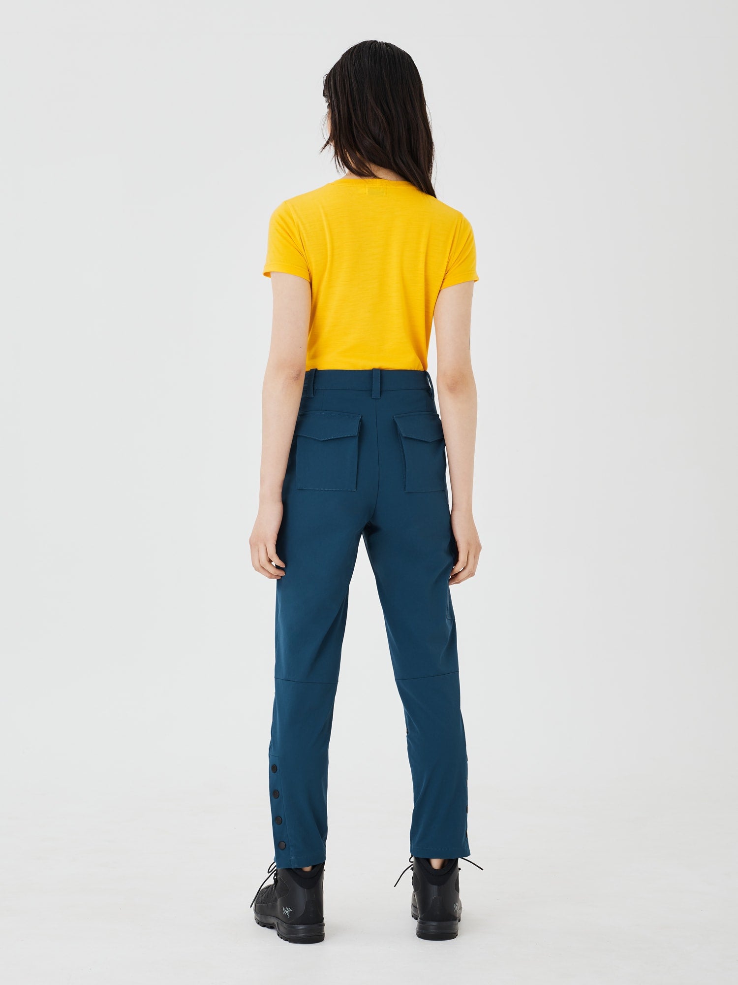 Full back view of blue Softshell Hiking Pants by Šumska, paired with a yellow classic merino T-shirt, showcasing the pants' stretch fabric and practical outdoor style.