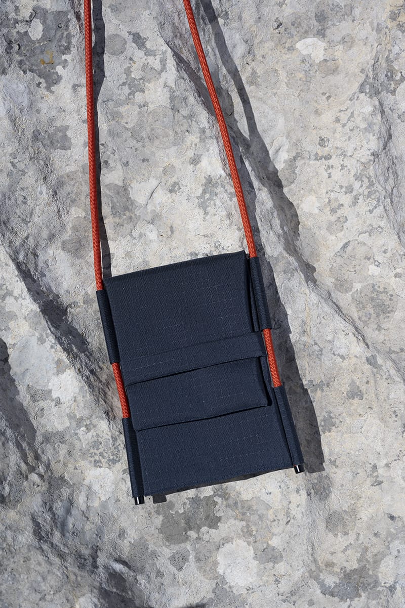 Šumska Crossbody iPhone Bag displayed against white granite rock.