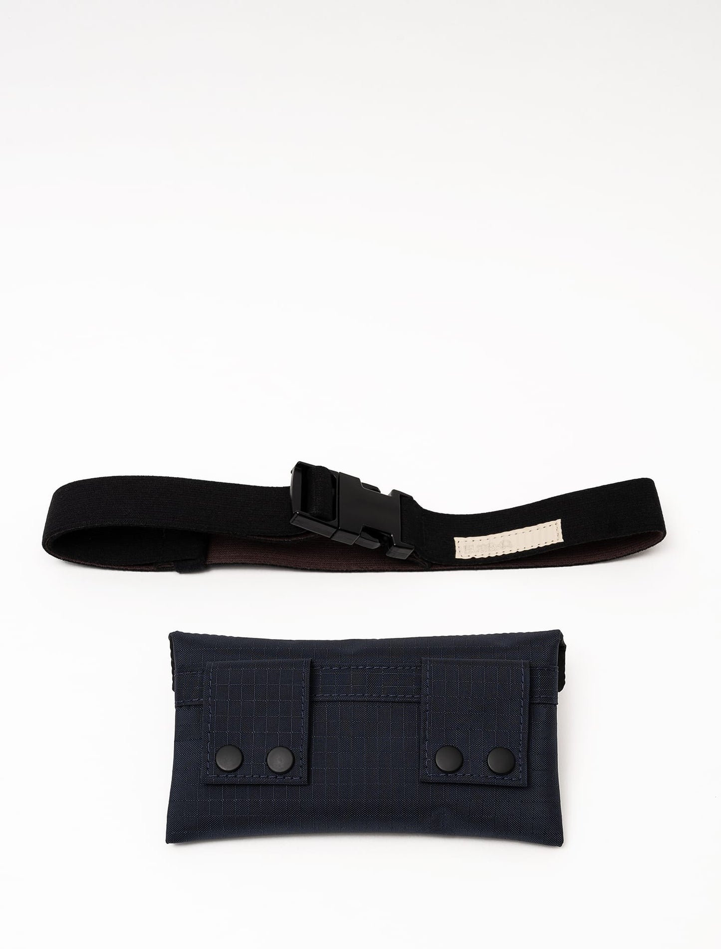 Back view of a midnight blue Cordura Belt Bag by Šumska, with the bag and belt unattached, displaying snap-button attachment loops.