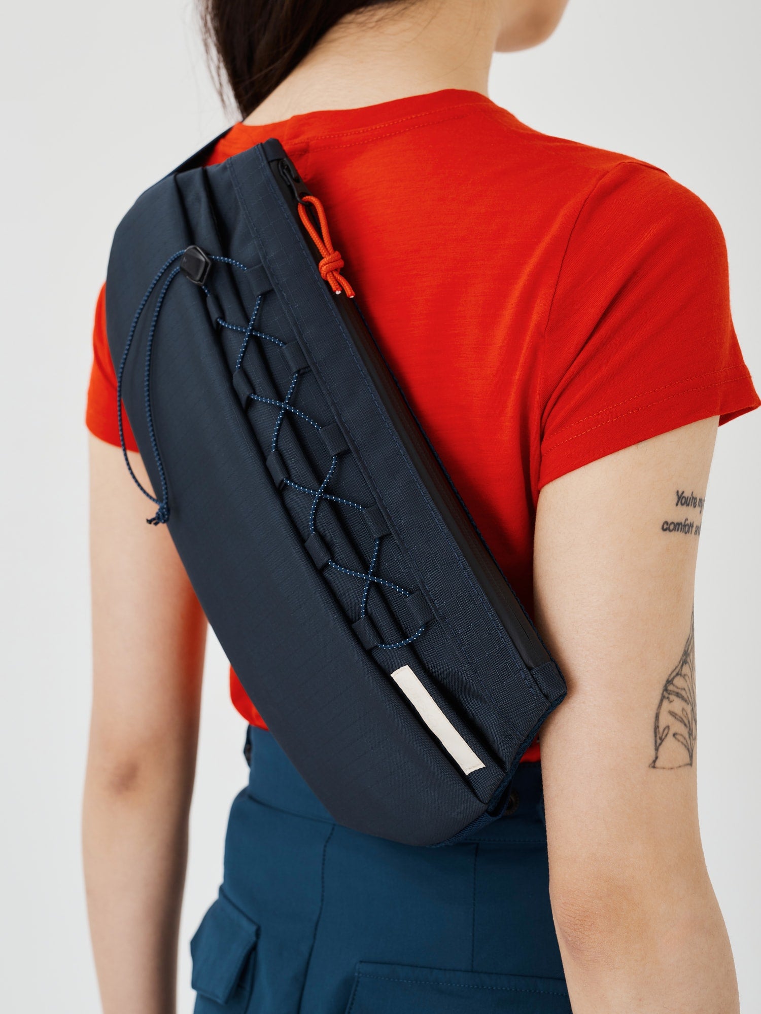 Zoomed-in view of the Šumska midnight blue Cordura sling bag worn on a woman's back, showing details like the adjustable elastic strap, durable Cordura fabric, and sleek design.