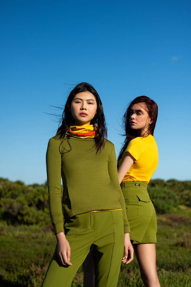 Two women, one wearing an olive green Merino Twiggy pullover with olive green softshell pants.