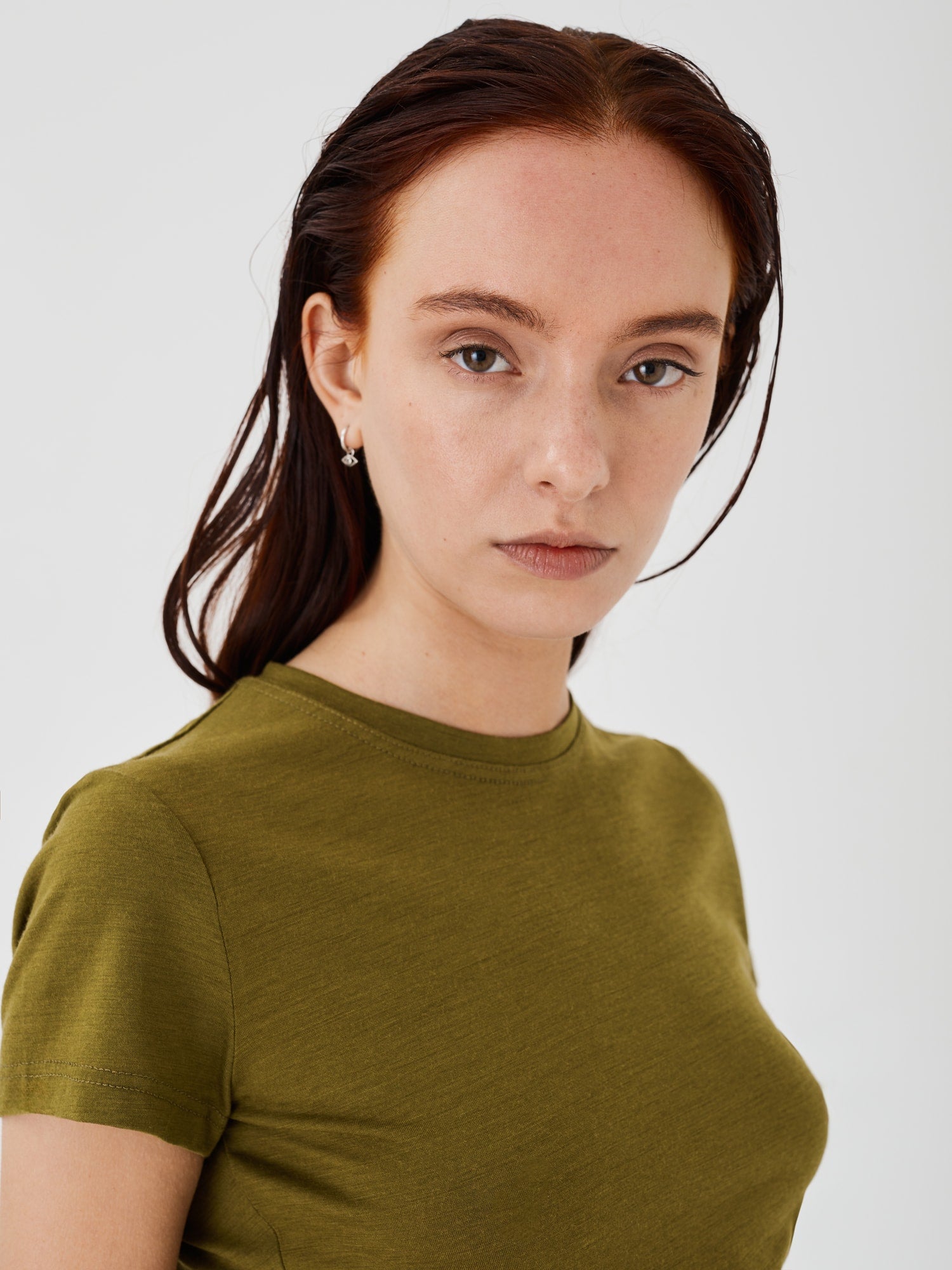 Zoomed-in view of a women's olive green merino wool classic T-shirt by Šumska, highlighting the fine fabric texture and stitching details.