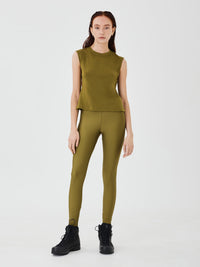 Full front view of a woman wearing olive green performance leggings by Šumska, paired with an olive green merino sleeveless T-shirt, highlighting a sleek, coordinated look and comfortable fit.