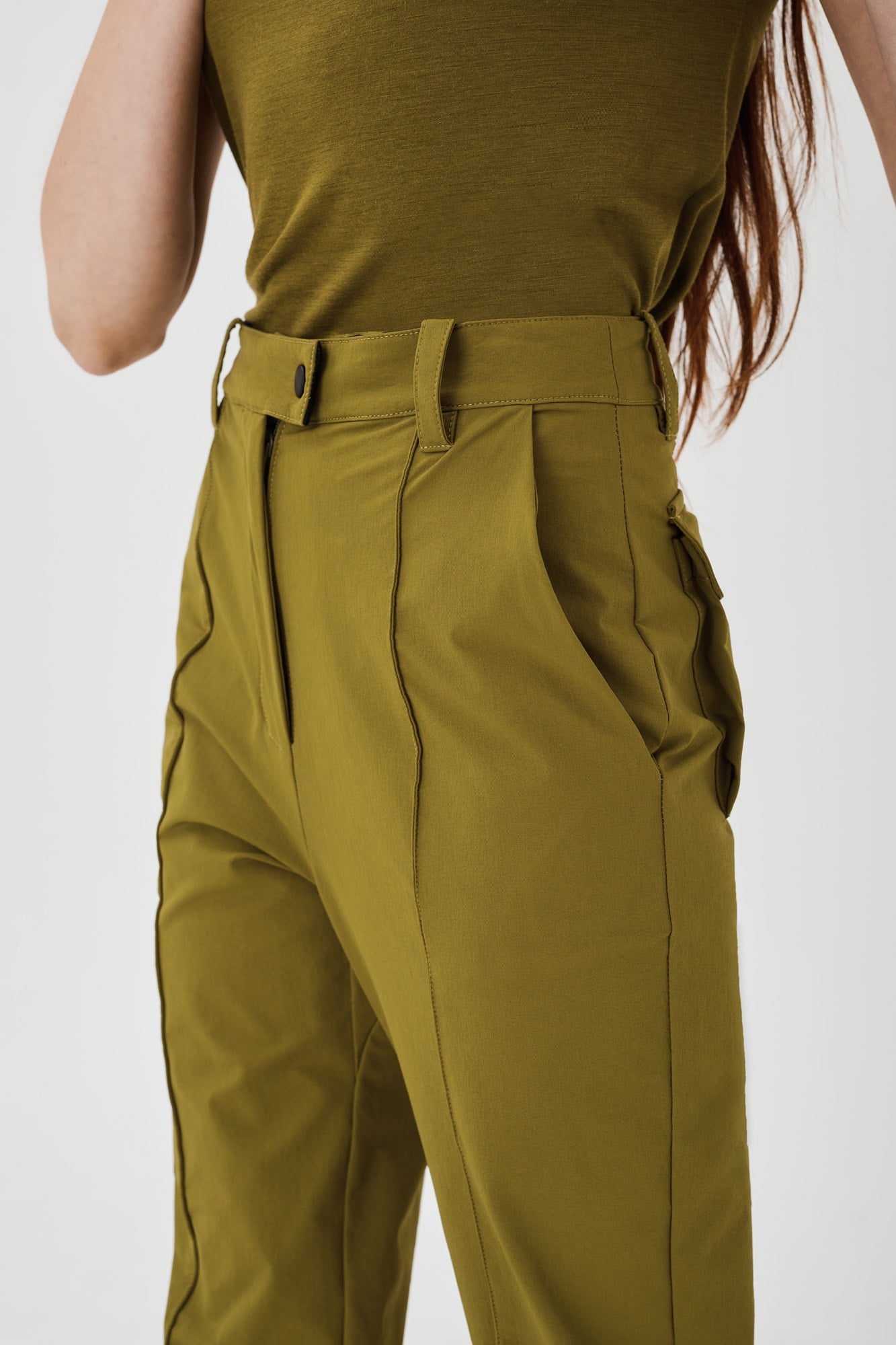 Close-up view of olive green Softshell Hiking Pants by Šumska, showing the fold seam, front pocket, and fine stitching details.