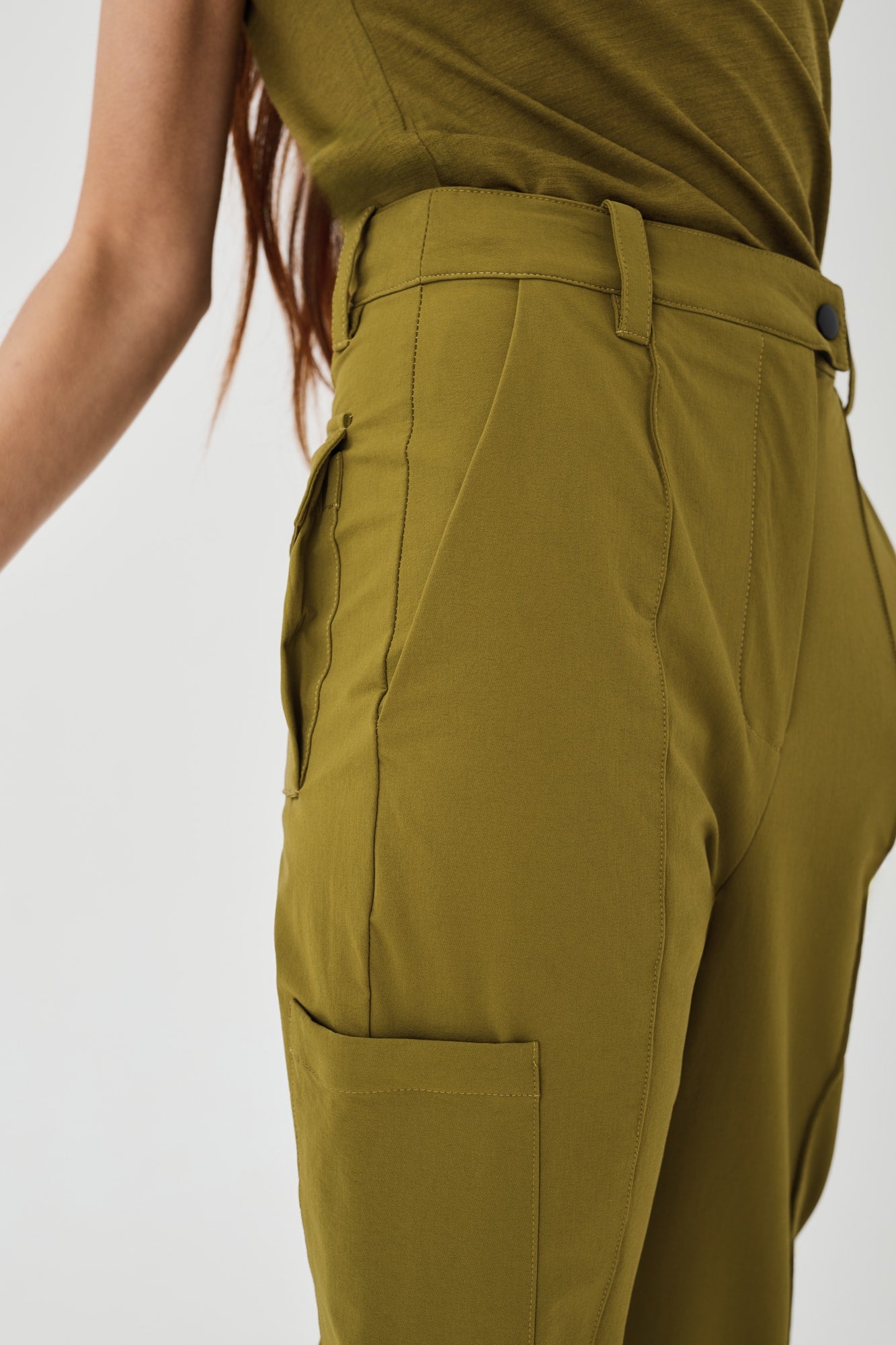 Close-up side view of olive green Softshell Hiking Pants by Šumska, showing construction details including the hand pocket, side pocket, and back pocket features.