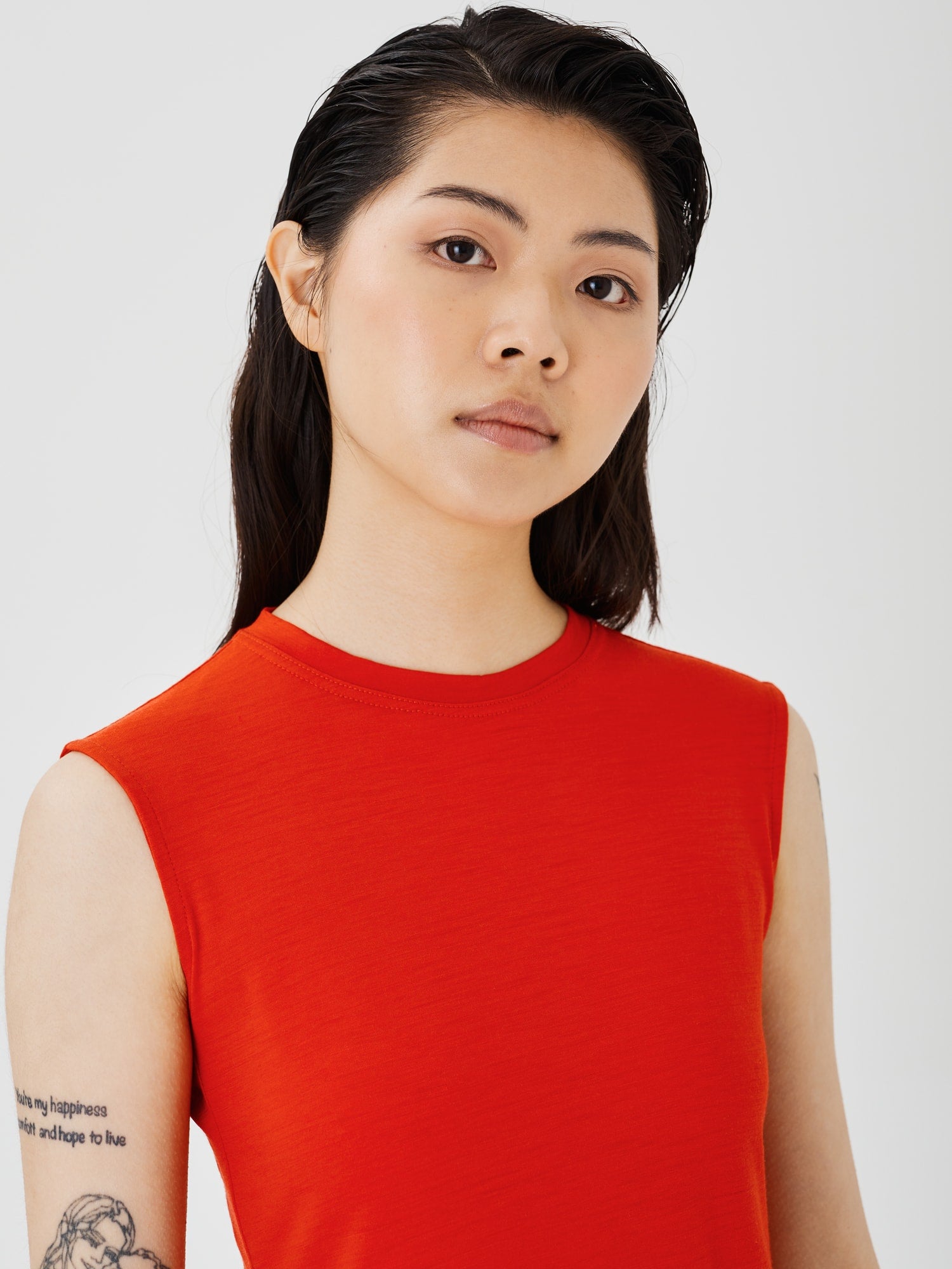 Zoomed-in view of a women's red merino wool sleeveless T-shirt by Šumska, highlighting the fine fabric texture and stitching details.