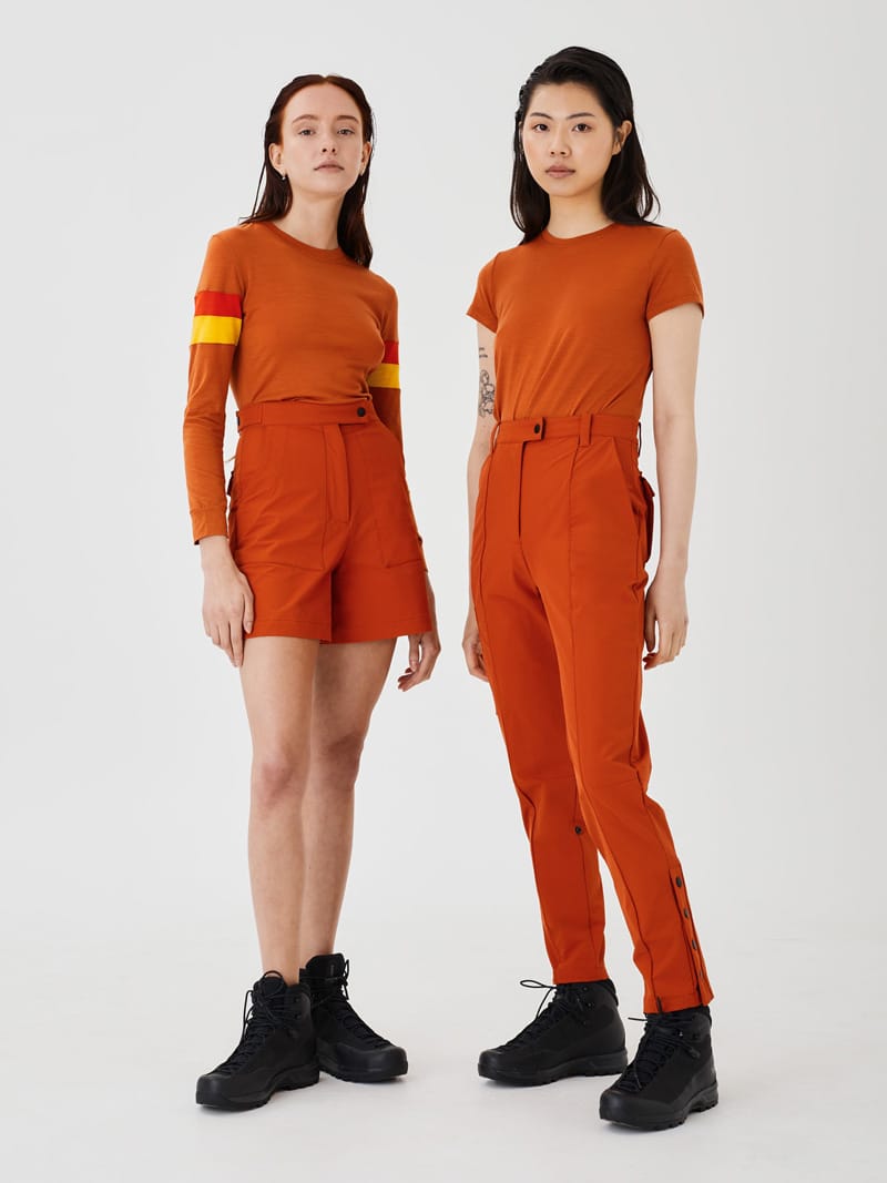 Two women wearing rust Merino tops paired with rust softshell shorts and pants