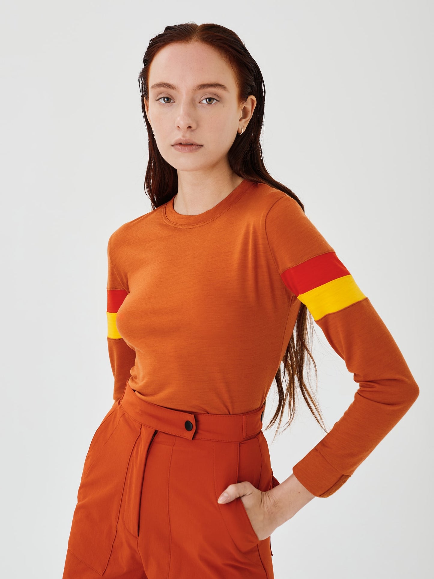 Close-up side angle view of a women's rust merino wool long sleeve top by Šumska, highlighting the fabric texture and sleek design.