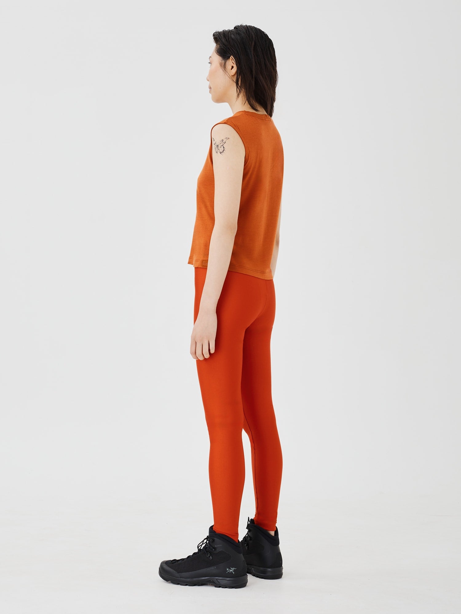 Back view of a women's rust merino wool sleeveless T-shirt by Šumska, showcasing the smooth fit and breathable design.