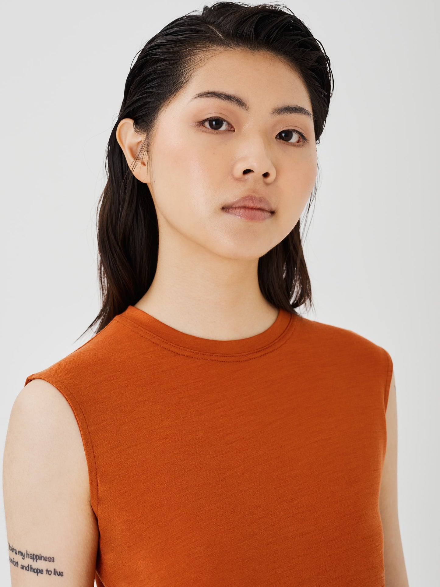 Zoomed-in view of a women's rust merino wool sleeveless T-shirt by Šumska, highlighting the fine fabric texture and stitching details.