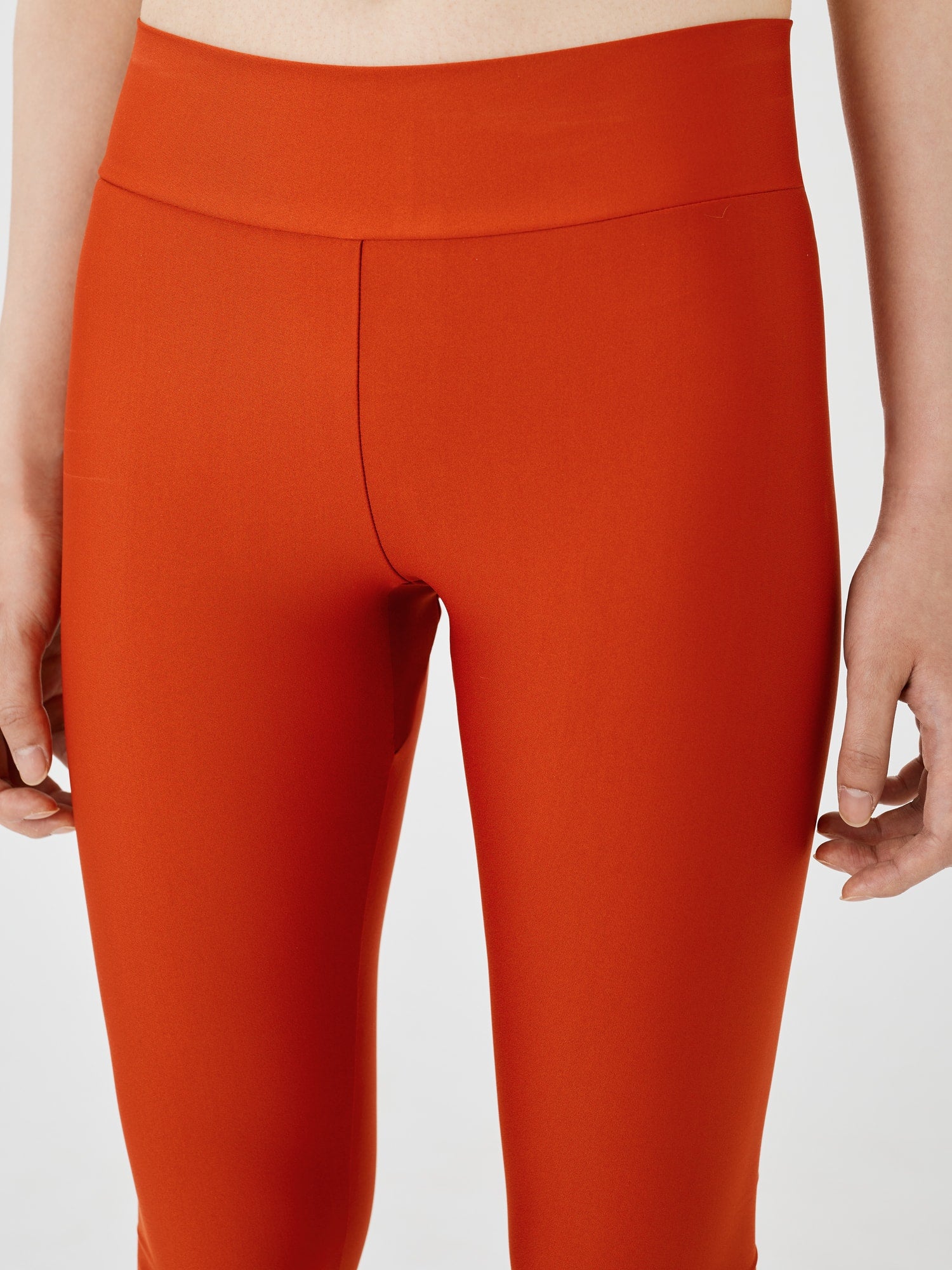 Close-up front view of rust-coloured performance leggings by Šumska, highlighting the sleek design, high waistband, and comfortable fit.