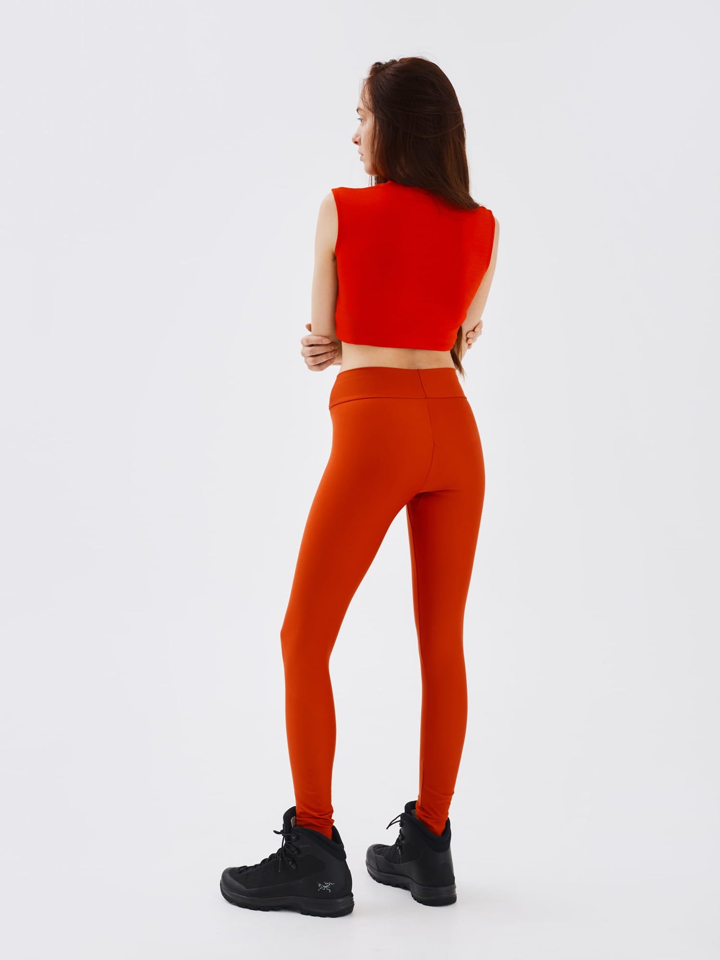 Full-body back view of a woman wearing rust-coloured performance leggings by Šumska, showcasing the supportive fit and seamless design.