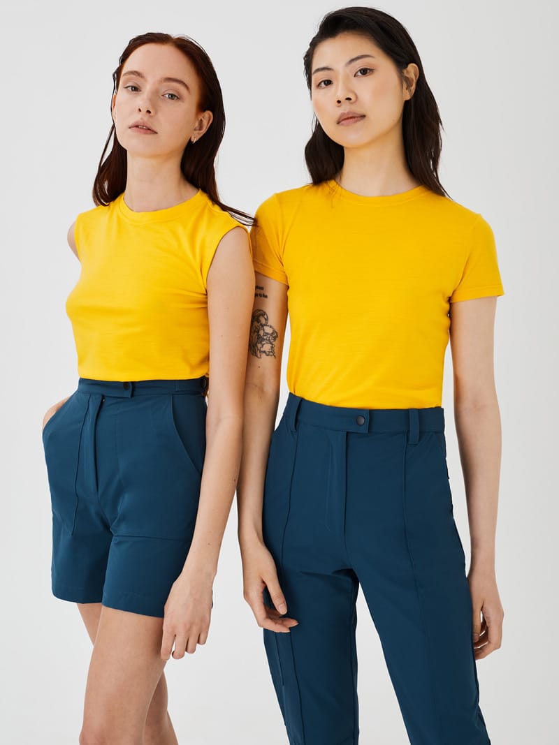 Two women wearing yellow Merino t-shirts with blue Softshell pants and shorts.