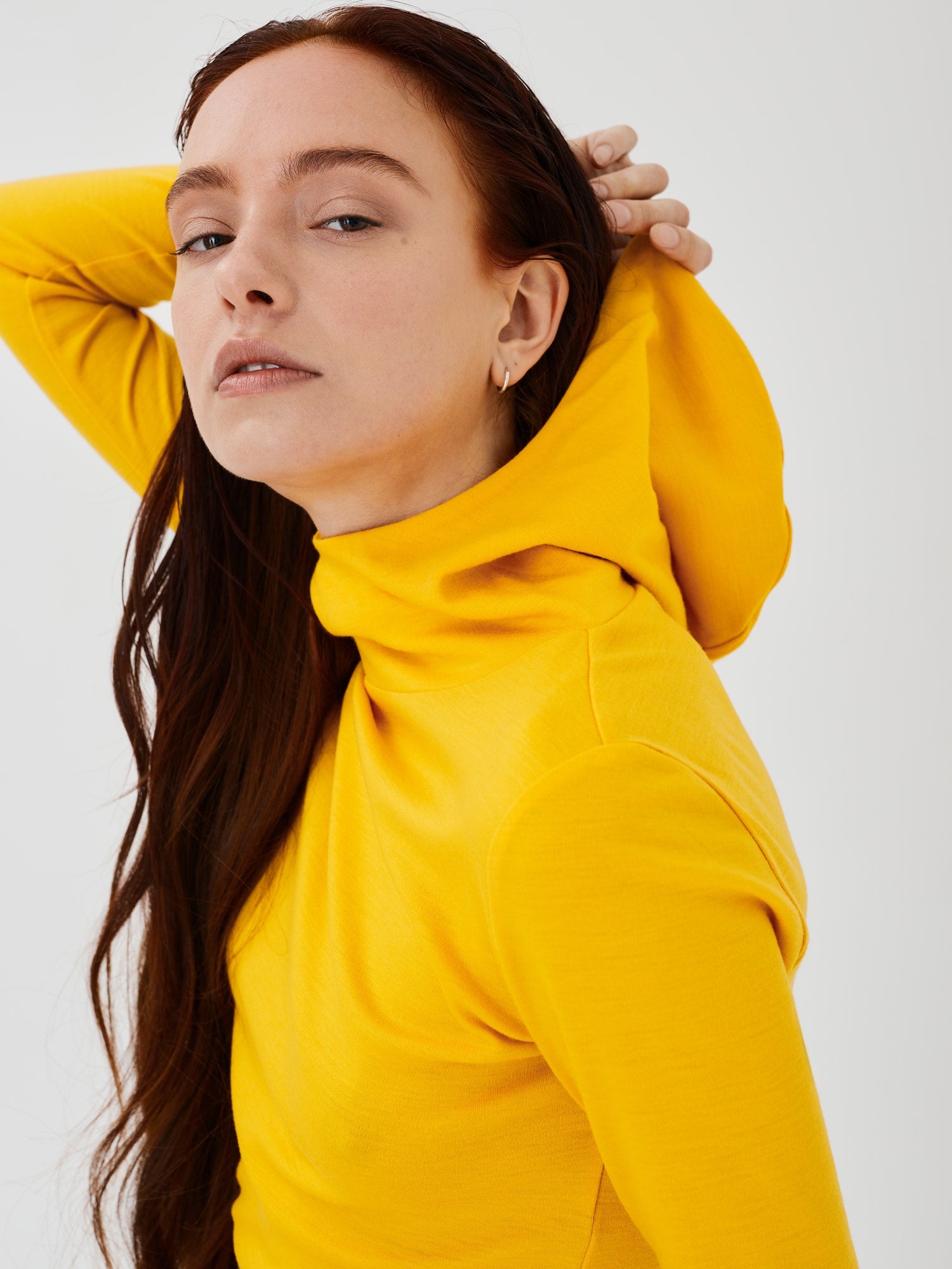 Front close side view of a women's yellow merino wool hoodie by Šumska, highlighting the clean, minimal design and cozy fit.