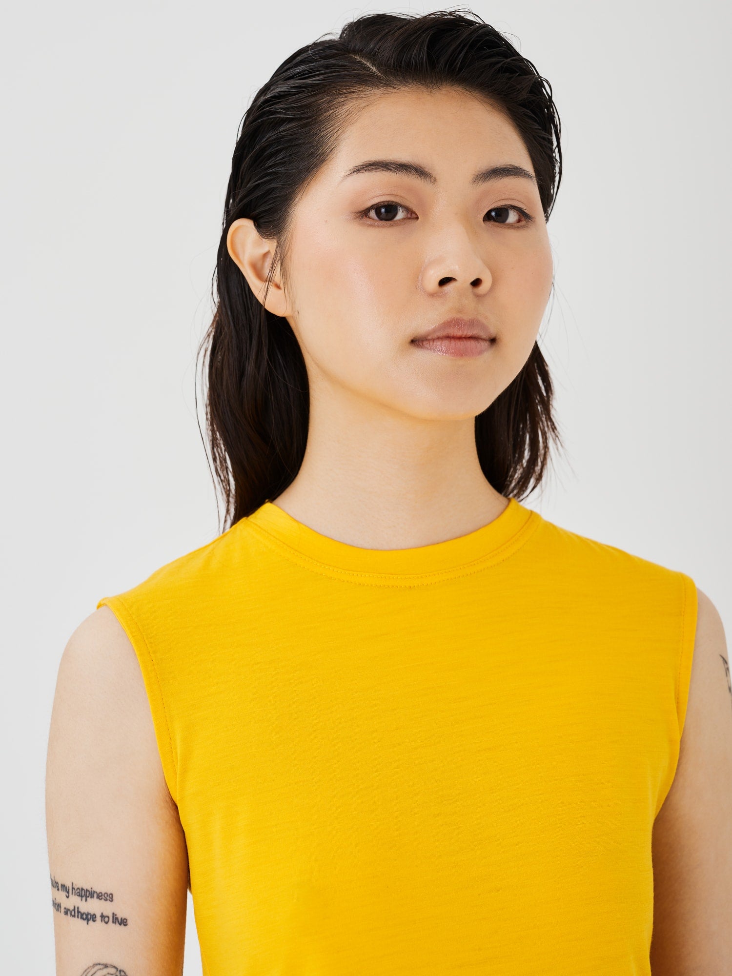 Zoomed-in view of a women's yellow merino wool sleeveless T-shirt by Šumska, highlighting the fine fabric texture and stitching details.